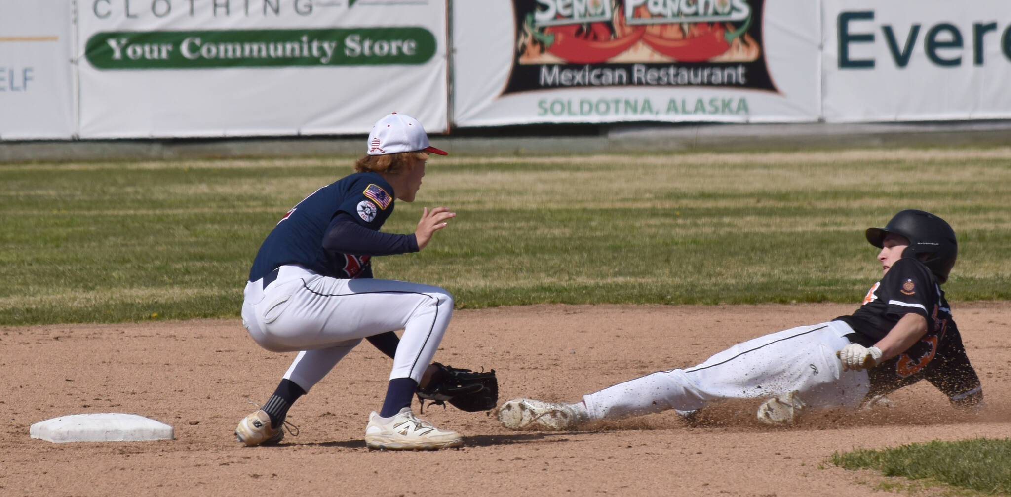 West’s Owen Tierney slides past the tag of Post 20 shortstop Jett Brophy on Friday, June 13, 2025, at Coral Seymour Memorial Park in Kenai, Alaska. (Photo by Jeff Helminiak/Peninsula Clarion)
