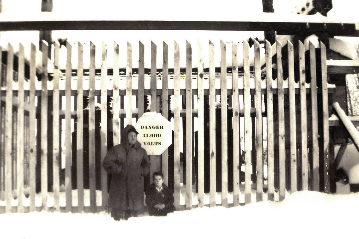 Frank Rowley and his youngest child, Raymond, stand in knee-deep snow in front of the protective fence around the main substation for Mountain View Light & Power in Anchorage in 1948 or ’49. This photo was taken a year or two before Rowley moved to Kenai to begin supplying electrical power to the central peninsula. (Photo courtesy of the Rowley Family)