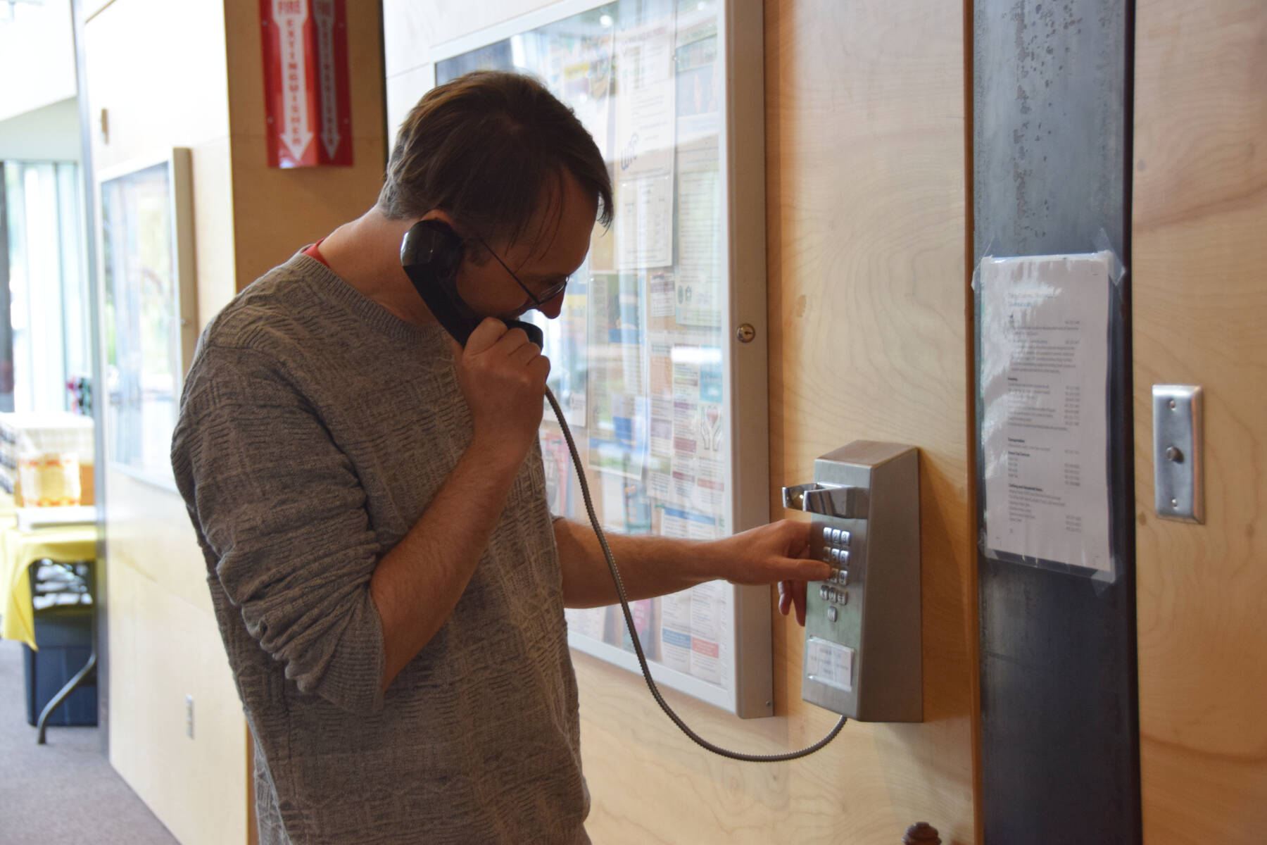Homer Public Library Director Dave Berry makes an outgoing call on the library’s public phone on Monday, July 7, 2025, in Homer, Alaska. (Delcenia Cosman/Homer News)