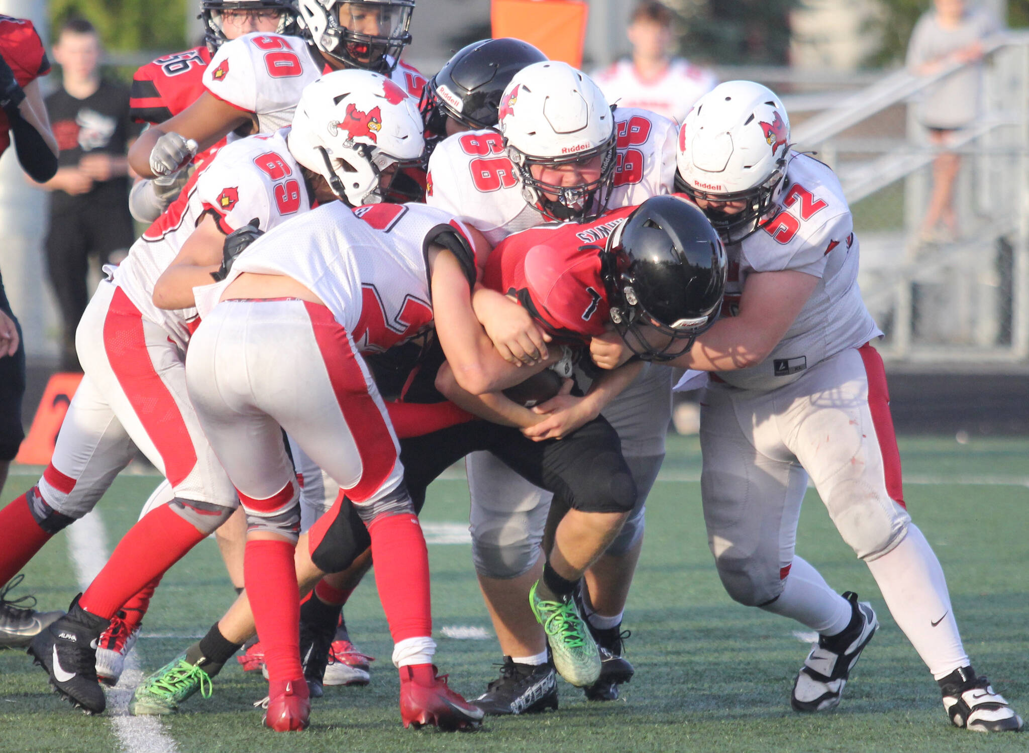 Kenai juniors Blake Morris (52) and Jackson Taliesin (66) lead a group of Kardinals as they bring down Houstons Mason Green during a 31-22 win over Houston on Friday, Sept. 5, at Houston High School in Houston, Alaska. (Photo by Jeremiah Bartz/Frontiersman)