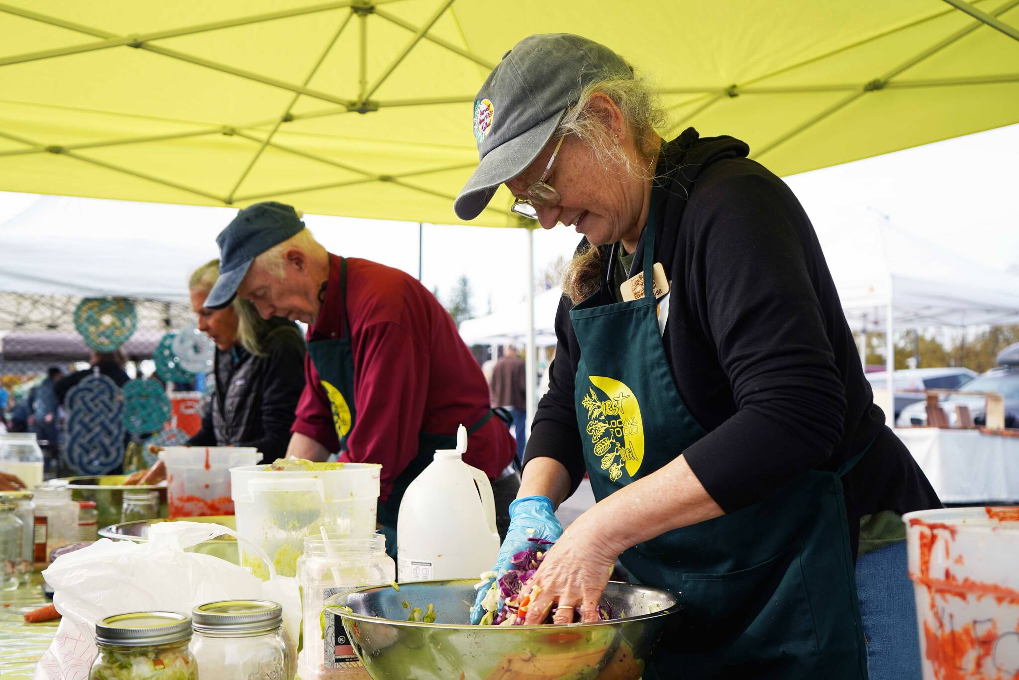 A line of volunteers man the fermentation station during the Harvest Moon Local Food Festival at Soldotna Creek Park in Soldotna, Alaska, on Saturday, Sept. 20, 2025. (Jake Dye/Peninsula Clarion)
