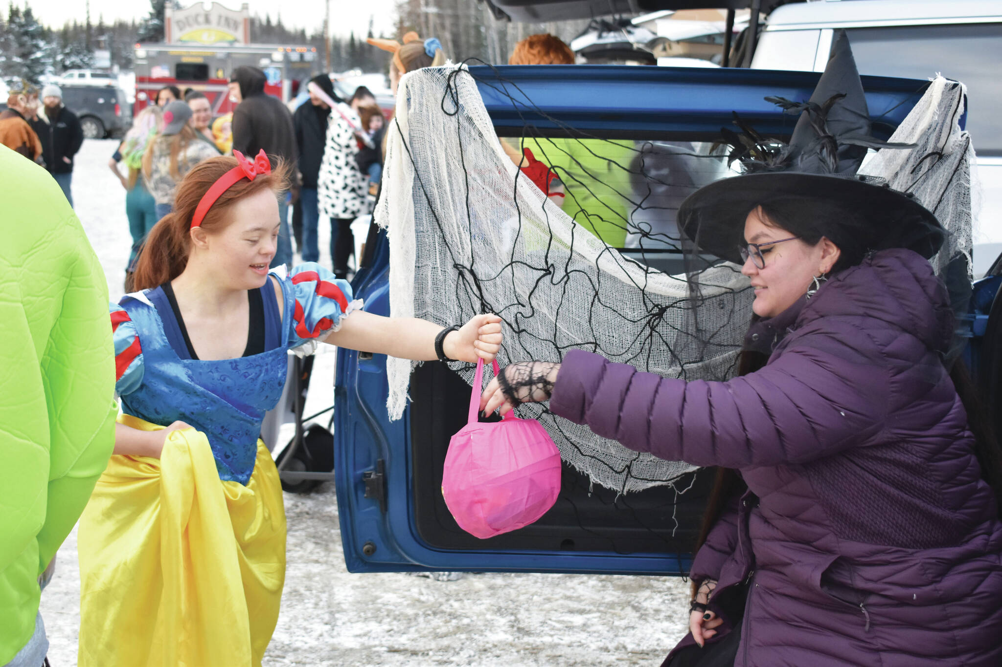 A girl dressed as Snow White takes candy from a witch at the Orca Theaters Trunk or Treat in Soldotna, Alaska, during Halloween in 2022. (Jake Dye/Peninsula Clarion)