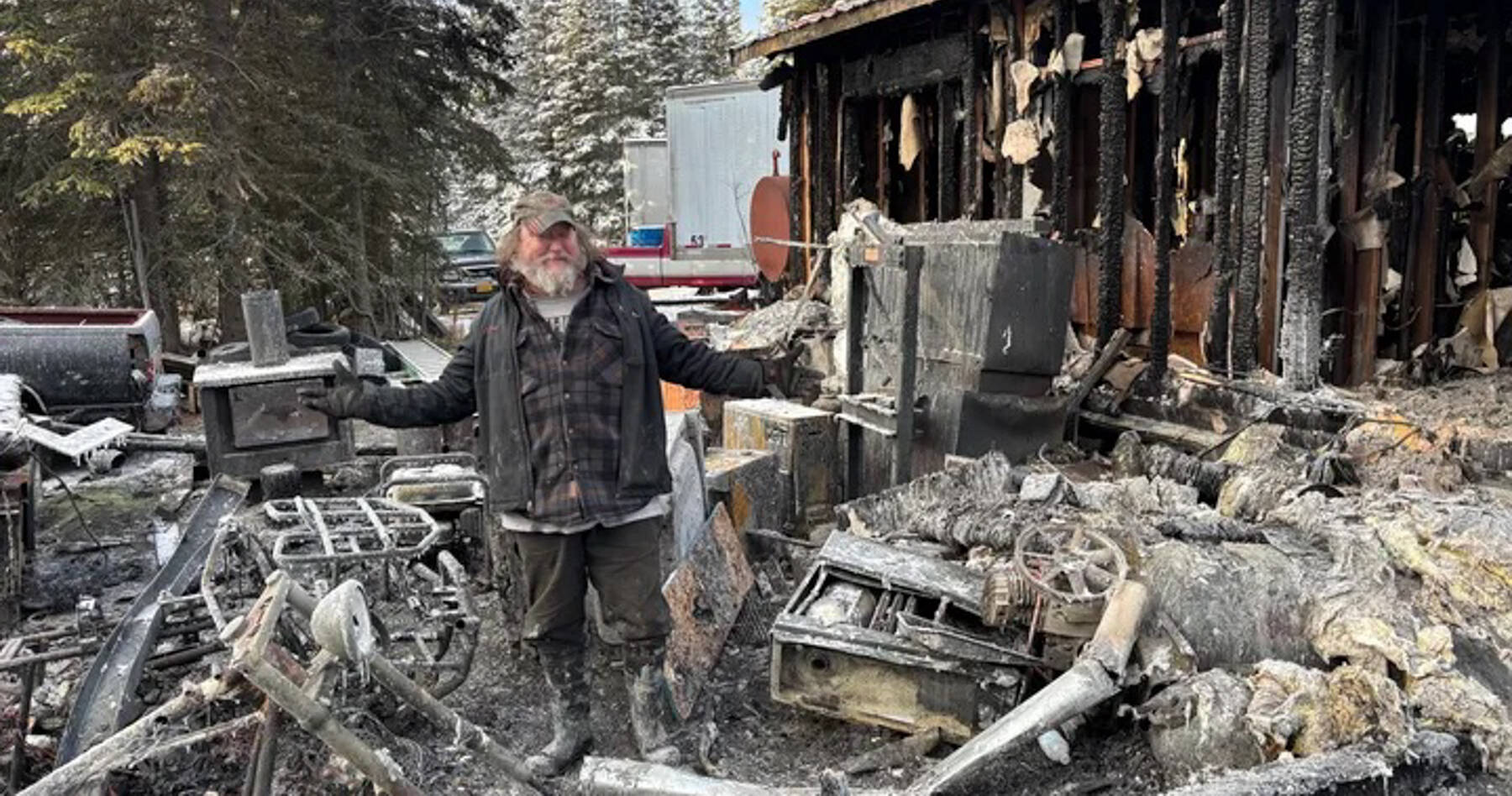 Clayton Whisamore stands in the remnants of his Kasilof home after a wood stove fire on Nov. 10, 2025. Whisamore couldn’t afford home insurance due to limited disability income, and his friends have organized a GoFundMe to help with the rebuild. Photo courtesy of GoFundMe