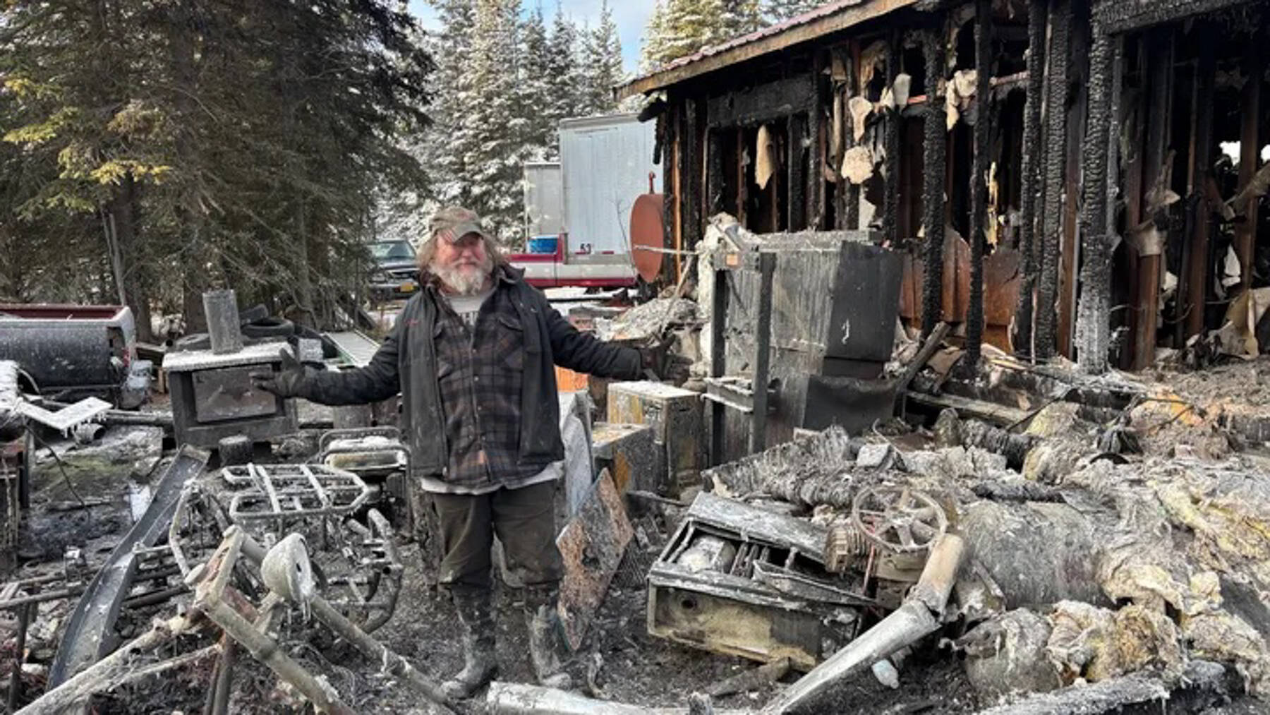 Clayton Whisamore stands in the remnants of his Kasilof home after a wood stove fire on Nov. 10, 2025. Whisamore couldn’t afford home insurance due to limited disability income, and his friends have organized a GoFundMe to help with the rebuild. Photo courtesy of GoFundMe