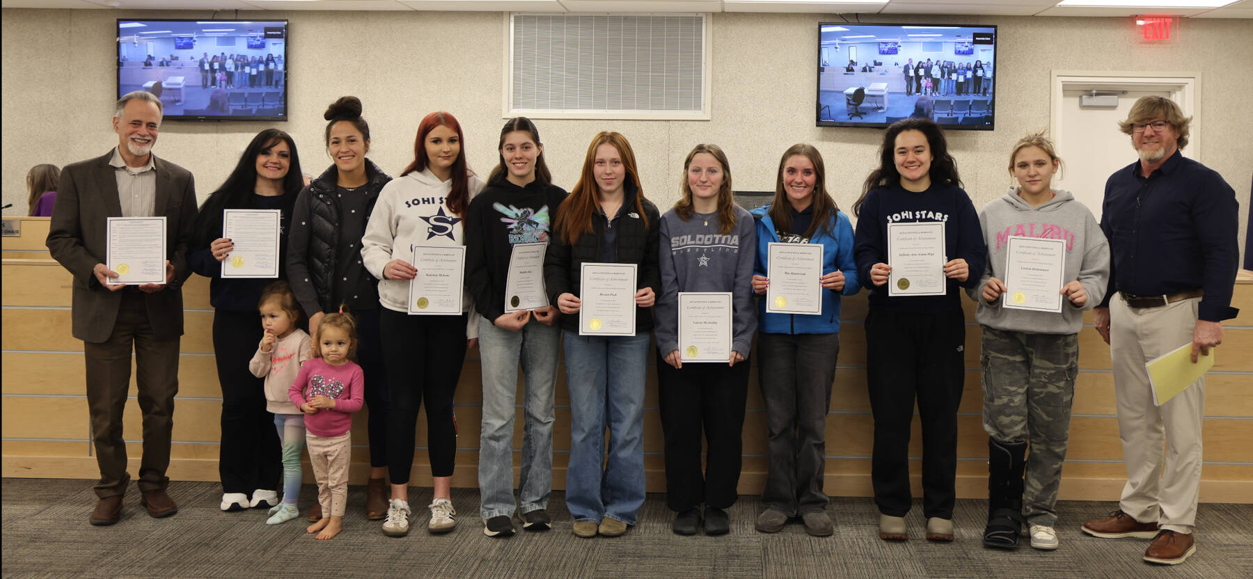 Photo courtesy of Sargeant Truesdell
Kenai Peninsula Borough mayor Peter Micchiche (left) and assembly member Sargeant Truesdell, District 4, Soldotna (right), pose for a photo with the Soldotna High School girls wrestling team during an assembly meeting on Jan. 20. The Stars secured SoHis first three-peat title during the state championship tournament Dec. 19-20.