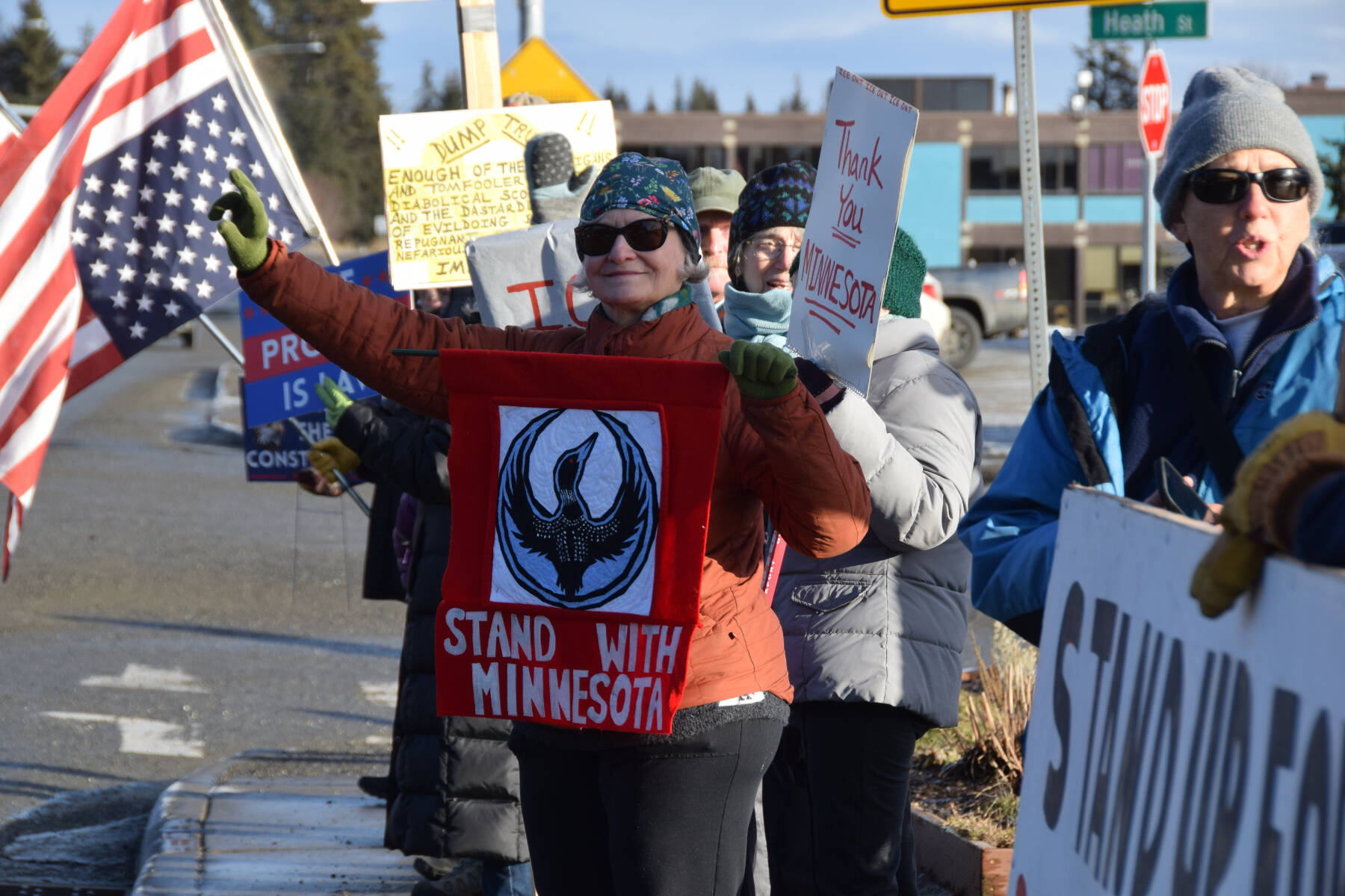 Jan Krehel waves at cars passing by as she holds a Stand With Minnesota banner during the ICE OUT demonstration on Sunday, Feb. 1, 2026, at WKFL Park in Homer, Alaska. (Delcenia Cosman/Homer News)