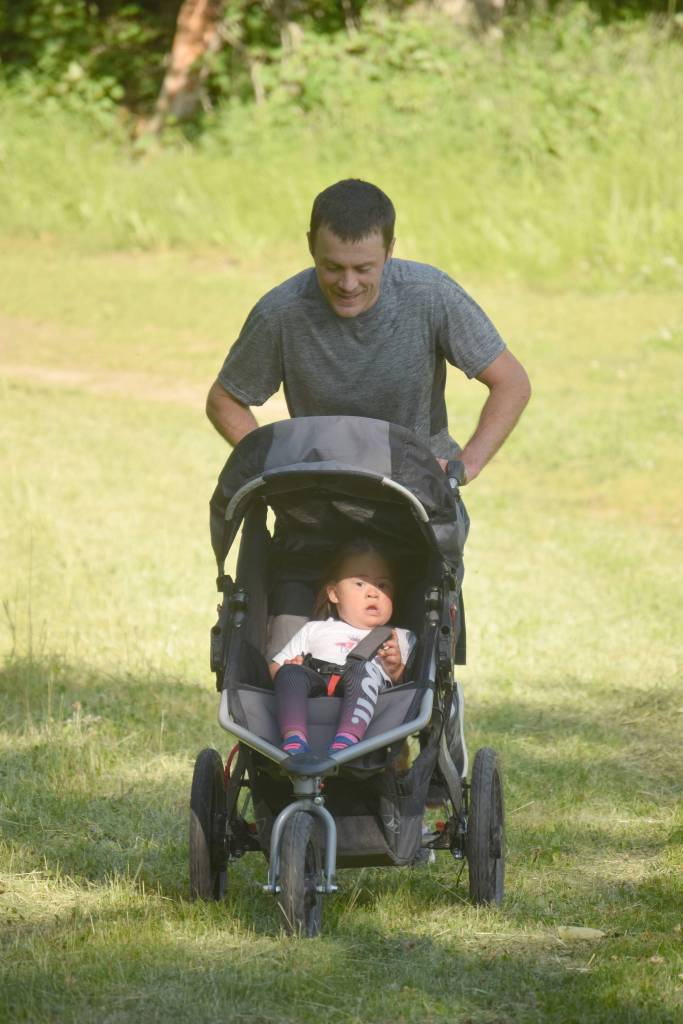 Jake Streich of Soldotna pushes his daughter, 3-year-old Harper, during the five-kilometer race Wednesday, July 18, 2018, during the Salmon Run Series at Tsalteshi Trails. (Photo by Jeff Helminiak/Peninsula Clarion)
