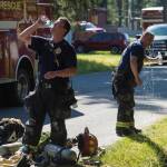 Capital City Fire/Rescue firemen attempt to cool off after fighting a house fire at 8460 Kimberly Street on Friday, July 20, 2018. (Michael Penn | Juneau Empire)