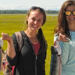 Anchorage residents Megen Draeger (left) and Athena Mallis (right) hold up the sockeye salmon they caught dipnetting in the Kenai River on Saturday, July 21, 2018 in Kenai, Alaska. (Photo by Elizabeth Earl/Peninsula Clarion)