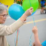 A volunteer in Heritage Places entry in the Progress Days parade hands a balloon to a young spectator on Marydale Avenue on Saturday, July 28, 2018 in Soldotna, Alaska. The parade kicks off the weekend-long event celebrating Soldotnas history, with a market on Saturday and Sunday in Soldotna Creek Park and a concert Saturday night followed by a free community barbecue Sunday. (Photo by Elizabeth Earl/Peninsula Clarion)