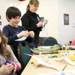 From left: Ahnalyse Kircheassner, 8 and Darius Garganl, 6, work to finish their paper Arctic Ters with help from teacher April Erhardt at STEAM Ahead on Jan. 28 at the Challenger Center of Alaska in Kenai.