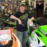 Photo by Dan Balmer Peninsula Clarion Arctic Motorsports owner Lane Giesler stands next two pro model Arctic Cat snowmobiles in his Soldotna shop Feb. 5. Giesler said the entire snow machine industry in Alaska has suffered due to the lack of snow this winter.
