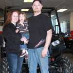 Photo by Dan Balmer Peninsula Clarion Nate and Hailey Titus pose with their daughter in front of a Polaris Ranger side by side at Peninsula Powersports. Nate Titus is the general manager and co-owner with Zack Johnston since the two went into business in 2006.