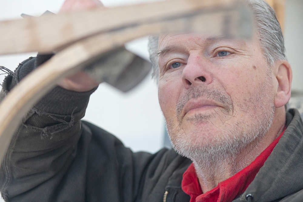 Photo by Rashah McChesney/Peninsula Clarion  Rod Perry does a bit of filing to fit a piece onto a wooden Iditarod sled he is building along with two friends Thursday Feb. 20, 2014 in Kasilof, Alaska.  The sled is much larger than any in use today and Perry said it was a replica of the type of sled originally used to haul freight, mail and passengers around the state.