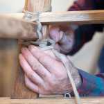 Photo by Rashah McChesney/Peninsula Clarion  Alan Perry lashes a portion of a wooden Iditarod sled he and two others are building for this year's race Thursday Feb. 20, 2014 in Kasilof, Alaska.