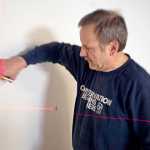 Photo by Rashah McChesney/Peninsula Clarion  Steve Greer holds a piece of slat wall in place Wednesday March 5, 2014 as he helps with renovations at the Kenai Fine Arts Center in Kenai, Alaska.