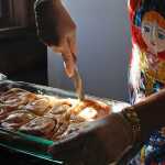 Photo by Rashah McChesney/Peninsula Clarion  Volunteer Dorothy Gray cuts into a fresh stack of cinnamon rolls while wearing one of the Russian-made aprons sold at Ft. Kenay Friday March 7, 2014 in Kenai, Alaska. Gray and others spend most of the day baking treats and selling them for "Fry Bread Friday" to benefit the Holy Assumption of the Virgin Mary Russian Orthodox Church.