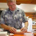 Photo by Rashah McChesney/Peninsula Clarion Volunteer Pat "Juney" Mullan packages a container of fry bread for a customer Friday March 7, 2014 at Ft. Kenay in Kenai, Alaska. Mullan, who spent a lot of his time joking with customers at "Fry Bread Friday" introduced himself as Feodor, Chelawek and Juney before settling on Pat.