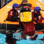 Classmates Donovan Orth and Seth Desiena learn to pull their peer out of cold water and into the safety of a life raft. Photo by Kelly Sullivan/ Peninsula Clarion