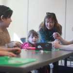 Photo by Kelly Sullivan/ Peninsula Clarion Troop Leader Cat Bras shows Ava Grossl, Bailey Smith, Allivia Grossl and Tash Grossl, how to properly install a small battery into their toothbrush robots, Saturday, March 22, at KPC in Soldotna.
