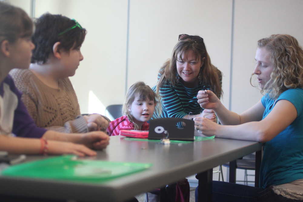 Photo by Kelly Sullivan/ Peninsula Clarion Troop Leader Cat Bras shows Ava Grossl, Bailey Smith, Allivia Grossl and Tash Grossl, how to properly install a small battery into their toothbrush robots, Saturday, March 22, at KPC in Soldotna.