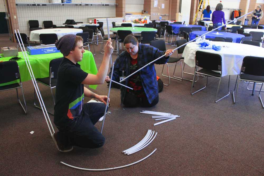 Photo by Kelly Sullivan/ Peninsula Clarion Will Fournier, Donna Valle and her dog Hopeful piece together the photo-booth frame for the Spring Fling, Friday, March 28, a the Soldotna Sports Center.