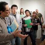 Photo by Rashah McChesney/Peninsula Clarion  Cam Choy, associate professor of Art at Kenai Peninsula College - Kenai River Campus, talks to one of his classes about a watercolor piece in the student art show Wednesday April 16, 2014 in Soldotna, Alaska.  The show will be on display through May 2 in the Gary L. Freeburg art gallery in the Brockel building.