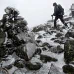 In this Saturday, April 5, 2014 photo, ice coats a rock cairn trail marker as Marielle Bergeron, of Quebec City, leads the way down Mount Adams in New Hampshire. Hikers wear crampons and use trekking poles for better balance in the treacherous conditions. (AP Photo/Robert F. Bukaty)