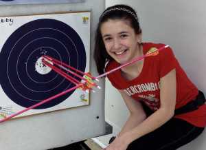 Photo courtesy DiPaolo family Abby DiPaolo poses next to her target from the  from the 2013 State Indoor 5 Spot Tournament. The sideways arrow actually hit another arrow and pierced the vein of the arrow.