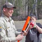 Photo by Rashah McChesney/Peninsula Clarion  U.S. Fish and Wildlife refuge operations sepcialist Dave Bolin demonstrates how he would check a shotgun during a role-playing session on law enforcement as Rocky Sherbahn takes a sip of his water Saturday May 3, 2014 during a Youth Game Warden camp at the Kenai National Wildlife Refuge Headquarters in Soldotna, Alaska.