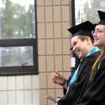 River City Academy graduates Kiowa Richardson (forward) and Shelby Fletcher (back) laugh as Principal Dawn Edwards-Smith talks about the class at the school's graduation ceremony on Wednesday at the Soldotna Regional Sports Complex. Kaylee Osowski/Peninsula Clarion