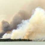 Photo by Rashah McChesney/Peninsula Clarion  Erik Huebsch, homeowner in the remote Bear Creek subdivision, is bathed in an eerie orange glow as smoke from the nearly 70,000 acre Funny River Wildfire obscures the sun over Tustumena Lake Friday May 23, 2014 in the Kenai National Wildlife Refuge. The fire has burned within a mile of the cabins, though Huebsch said he is hopeful as the wind has changed directions and could burn the bulk of the blaze away from the cabins.