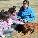 Kindergartener Jenesys Vandermartin (left) and fourth grader Shraddha Davis (center) pet Lucy, the dog, as Katie Moon (right), Lucy's owner, sits with them. The two students read to Lucy at Kalifornsky Beach Elementary School in Soldotna on Tuesday, May 20. Photo by Kaylee Osowski/Peninsula Clarion