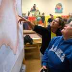 Photo by Rashah McChesney/Peninsula Clarion Sue Krafft, left, and Denise Dutile, look at a map of the Funny River Horse Trail wildfire Monday May 26, 2014 during a community meeting for evacuees from Funny River Road in Soldotna, Alaska. The fire has consumed at least 176,000 acres of Kenai National Wildlife Refuge land.