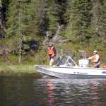 Three agencies work together to spread fluridone pellets to eradicate elodea. Scott Schuler, SePRO, works the hose, John Morton, Kenai National Wildlife Refuge, drives and Matt Steffy, Homer Soil and Water Conservation District, fills the hopper for pellet spreader. Photo courtesy of Kenai National Wildlife Refuge