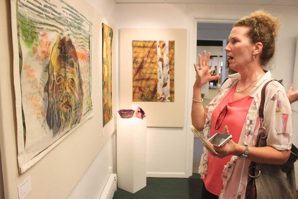 Photo by Kelly Sullivan/ Peninsula Clarion Laurie Marta reacts to Sandra Sterling's quilt piece that incorporates silk and dying to create a three dimensional effect, June 6, at the Kenai Fine Arts Center.
