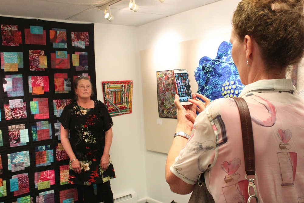 Photo by Kelly Sullivan/ Peninsula Clarion Laurie Marta takes a picture of Lynn Mettille in front of the quilt Mettille made, June 6, at the Kenai Fine Arts Center.