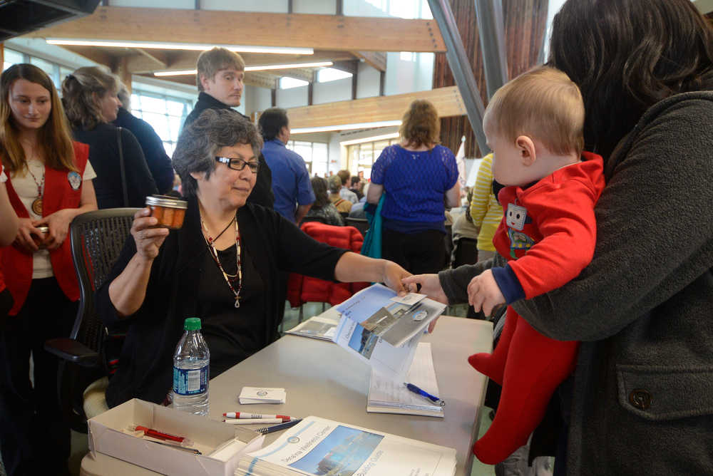 Photo by Rashah McChesney/Peninsula Clarion  Elsa Maillelle hands a jar of salmon to a visitor during the grand opening ceremony of the Kenaitze Indian Tribe's Dena'ina Wellness Center Thursday June 12, 2014 in Kenai, Alaska.
