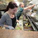 Photo by Rashah McChesney/Peninsula Clarion  Megan Schaafsma makes a sandwich as Ruari Tuite works alongside her at Odie's Deli Wednesday June 18, 2014 in Soldotna, Alaska. Schaafsma is buying the business from longtime owner Melodie Symington who first opened the deli in 2005. Schaafsma will take over both the Kenai Airport and Soldotna locations.