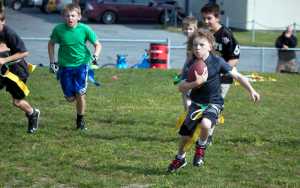 Photo by Dan Balmer/Peninsula Clarion Reagan Graves,9, carries the ball while Noah Harper, 10 attempts to pull his flag during a football scrimmage Monday at Soldotna High School. Nearly 50 kids participated in the Kenai Peninsula Youth Football Camp, led by Soldotna High football coach Galen Brantley. The camp, open to kids through eighth grade, runs through Wednesday.