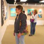 Photo by Kelly Sullivan/ Peninsula Clarion Rosalie Vass looks on at one of Kaitlin Vadla's acrylic paintings, Thursday, July 24, at the Kenai Fine Arts Center.