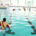 Photo by Kelly Sullivan/ Peninsula Clarion Gracee Braun lays patiently as Landon Lightfoot practices strapping her into a water rescue stretcher, June 30, at the Nikiski Pool.
