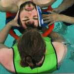 Photo by Kelly Sullivan/ Peninsula Clarion Landon Lightfoot lays patiently as Janet Gaftenby practices strapping him into a water rescue stretcher, June 30, at the Nikiski Pool.