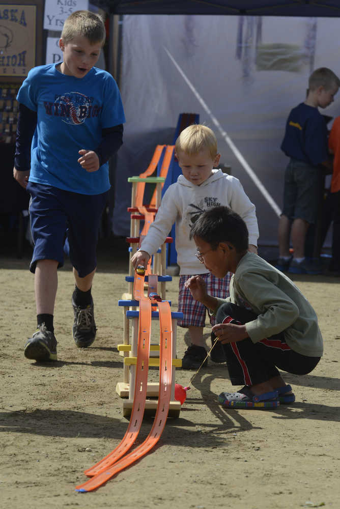 Photo by Rashah McChesney/Peninsula Clarion  (left) Gus Miller, 9, Silas Hamilton, 3, and Michael Greist Beltz, 7, play with cars during the Soldotna Progress Days festival Saturday at the Soldotna Little League Fields.