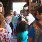 Photo by Kelly Sullivan/ Peninsula Clarion Kenai Wildlife Refuge park ranger Leah Eskelin talks about what it was like to sleep in a log cabin in the middle of winter to her groupd of participants in the Family Explorer Program, Saturday, August 2, 2014, on the Keen-Eye Nature Trail in Soldotna.