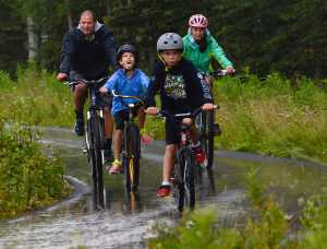 Photo by Rashah McChesney/Peninsula Clarion  (left) Chad Arthur bikes with his kids, Erika Arthur, 11, Andrew Arthur, 8, and Kellie Arthur, 13, during a rainstorm Sunday August 3, 2014 in Kenai, Alaska.  Chad Arthur said the group was headed to Don Jose's restaurant.