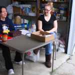 Photo by Kelly Sullivan/ Peninsula Clarion Miranda Bicknell, 19, and her younger sister Kelsey, 18, talk in the garage beside the six-family garage sale held at their grandmothers house, Saturday, August 9, 2014, in Soldotna, Alaska.