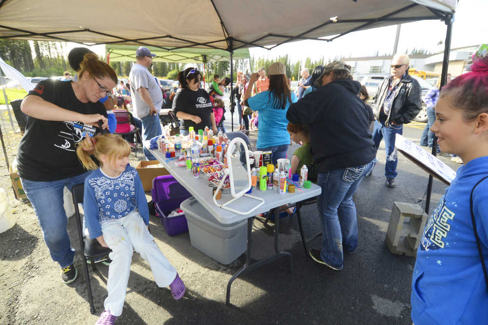Photo by Kelly Sullivan/ Peninsula Clarion Shannette Wik creates a wild hair style for Arianna Steadman, while Brayleigh Steadman watches on at the Kenai Peninsula Borough, Kenai Peninsula College and Kenai Peninsula Borough School District joint 50th anniversary community barbecue, Thursday, August 14, at the KPC Kenai River Campus in Soldotna, Alaska.