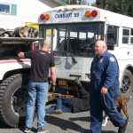 Photo by Dan Balmer/Peninsula Clarion Michael Rogers (right) from the Alaska State Troopers Bureau of Highway Patrol Commercial Vehicle Enforcement finished an inspection of a bus after it was pulled from the woods following a crash early Sunday morning in Soldotna. Troopers reported the bus driver died from natural causes after he went unconscious and veered off the road at Mile 90 of the Sterling Highway. Seven employees from Snug Harbor Seafoods were injured in the crash and transported to Central Peninsula Hospital for non-life threatening injuries. Buddy Lindson (ground) and Mike Walters (left) from Buddy's Garage in Soldotna, prepare to tow the bus away from Fellman Machinery.