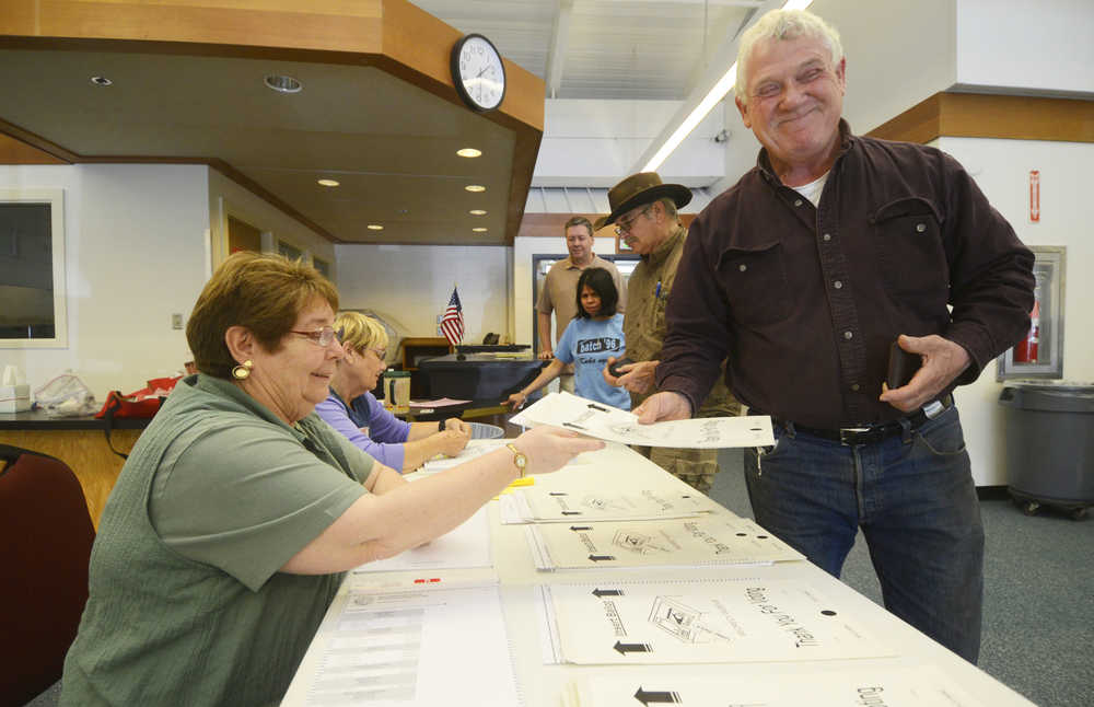 Photo by Kelly Sullivan/ Peninsula Clarion Willie Porter takes his ballot from volunteer Dolores Wik, at the Nikiski Recreation Center Tuesday, August 19, 2014, in Nikiski, Alaska.